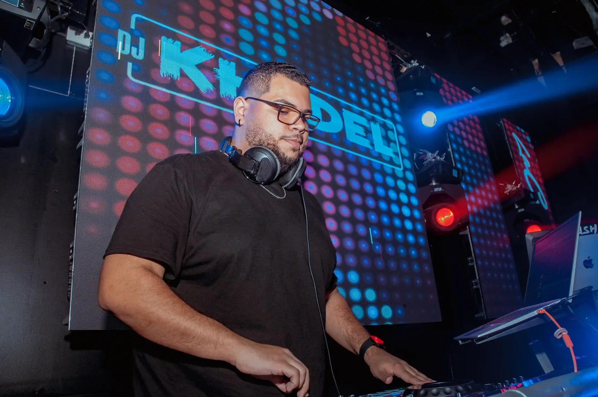 DJ Khedel mezclando frente a una pantalla con su nombre